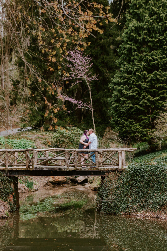 A couple kissing while standing on an old wooden bridge. 