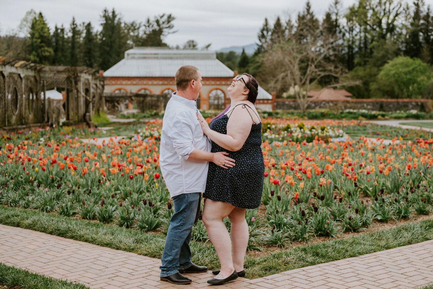 Biltmore estate engagement photos featuring a couple laughing with their arms around each other in a colorful garden.