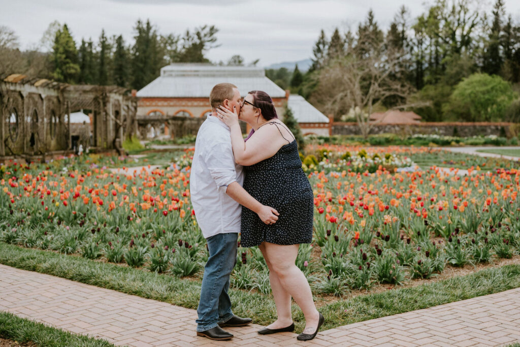 Couple kissing while standing in a colorful garden. 