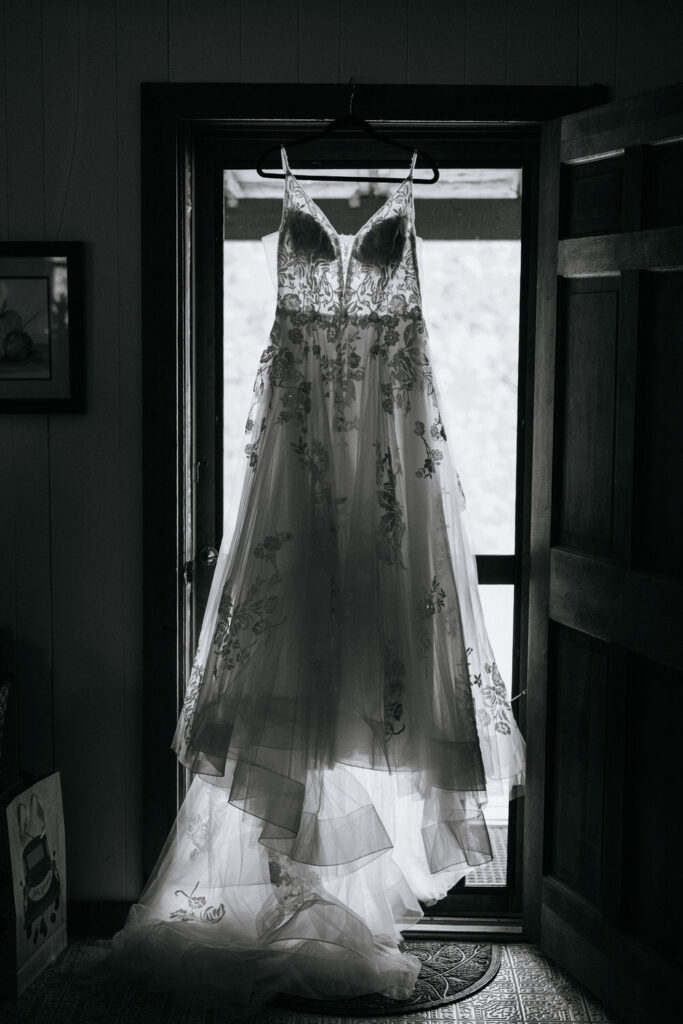 Black and white photo of a wedding dress hanging in a window
