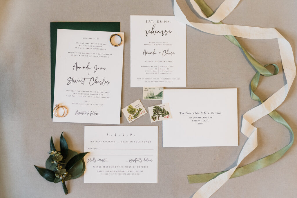 Wedding invitations laid out on a table with the wedding bands on top of them. 