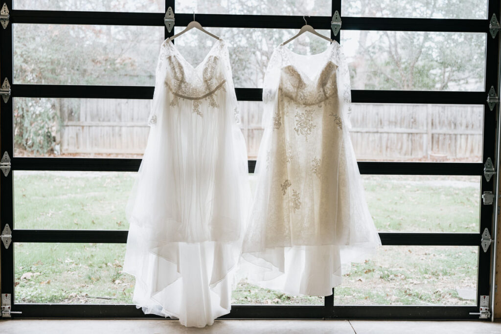 Two wedding dresses hanging up next to each other. 