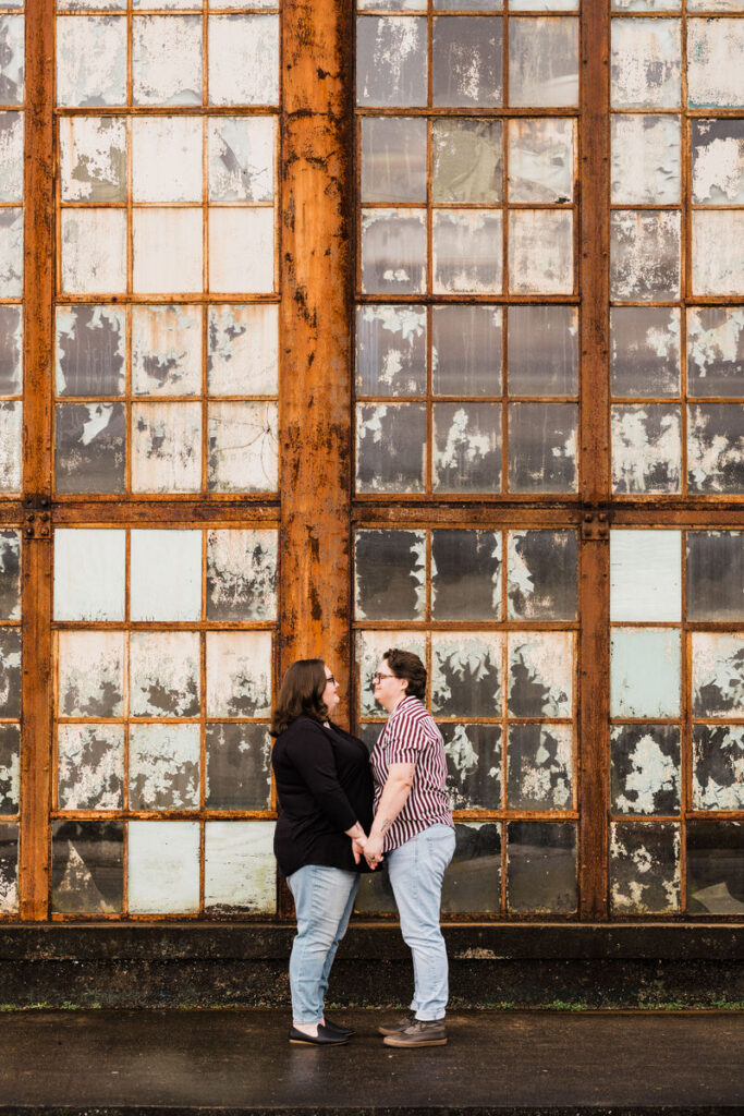 A couple standing in front of a large wall of windows. 