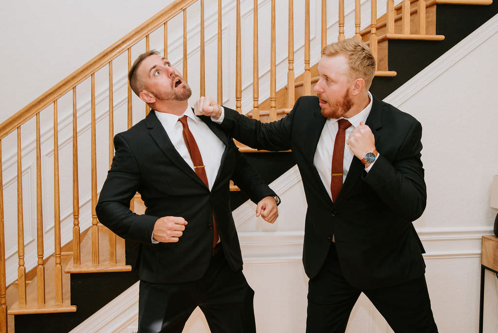 A groom fake punching a groomsmen before a wedding. 