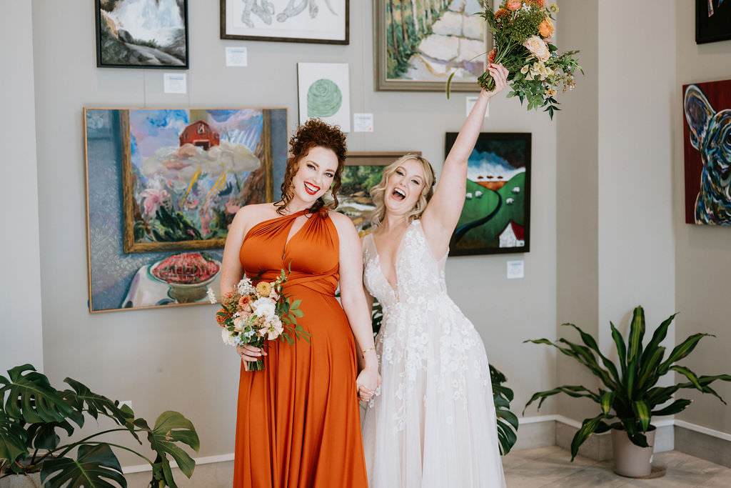 A bride standing with her bridesmaid as she holds up her bouquet. 