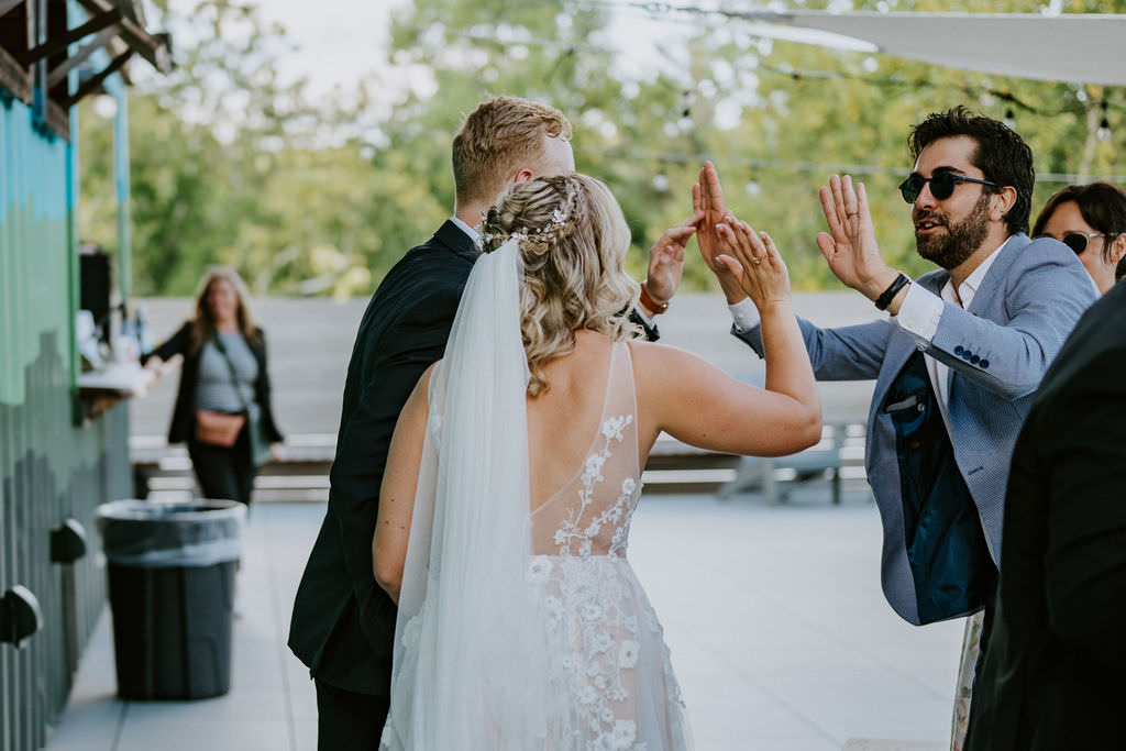 A bride and groom walking back up the aisle after getting married and high-fiving a guest. 