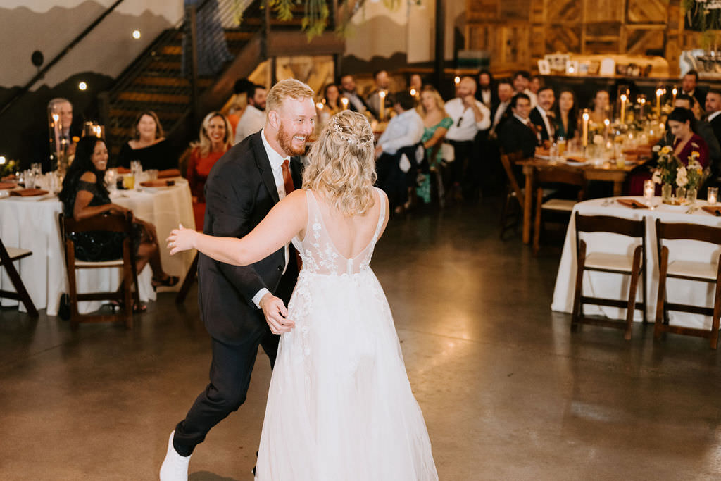 A bride and groom during their first dance with their guests watching from behind. 