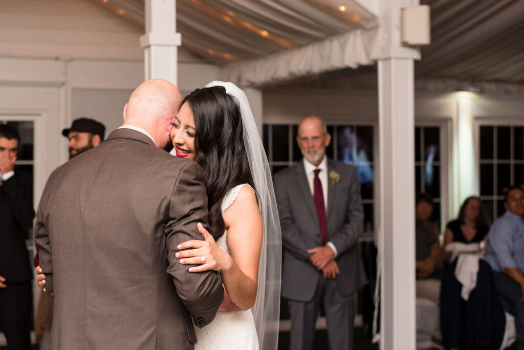 A couple smiling and dancing during their first dance. 
