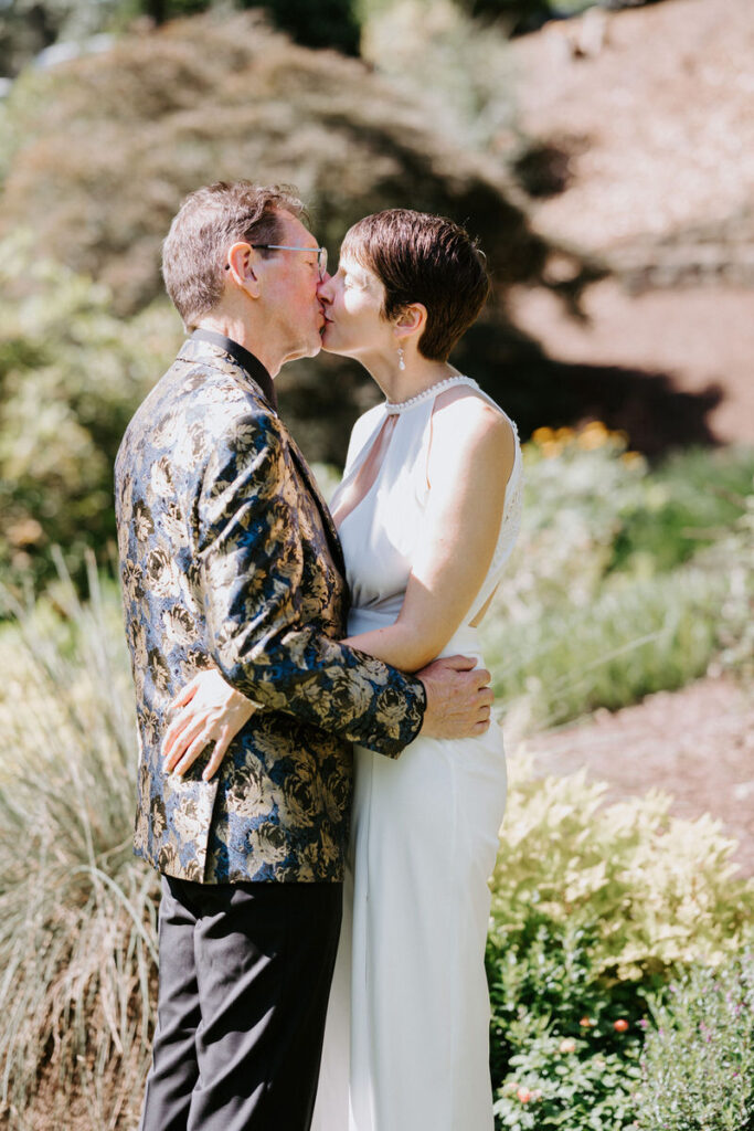 A wedding couple kissing in a garden. 
