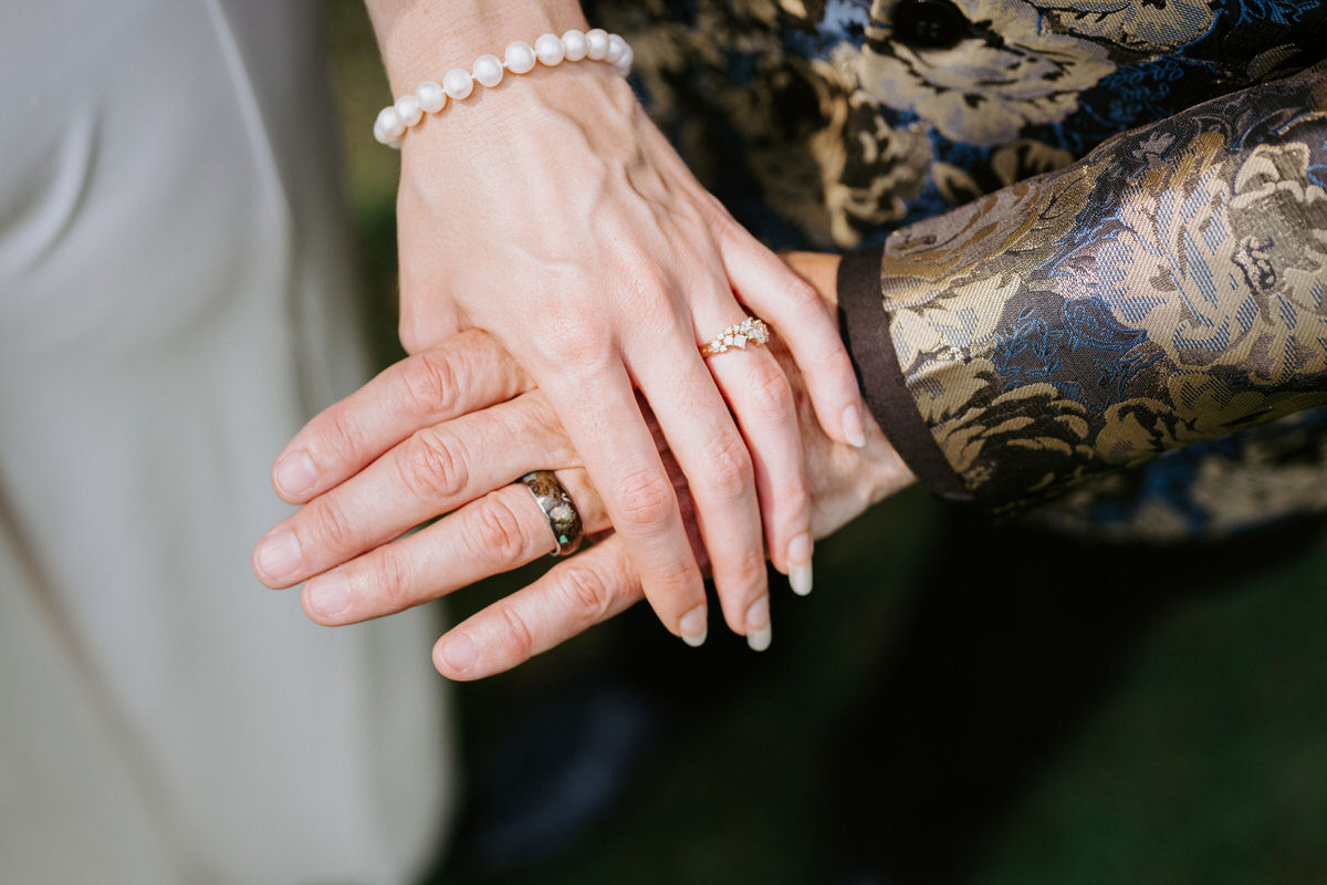 Two people's hands stacked on top of each other showing off wedding rings showing how to elope in South Carolina.