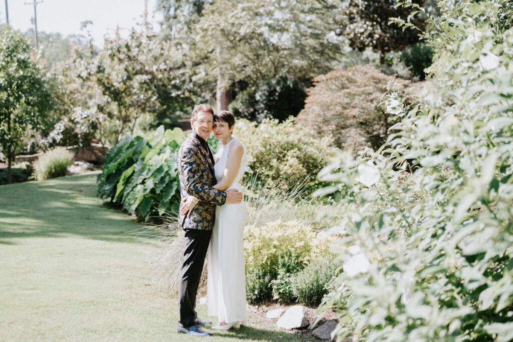 A couple hugging with their heads touching in a garden. 
