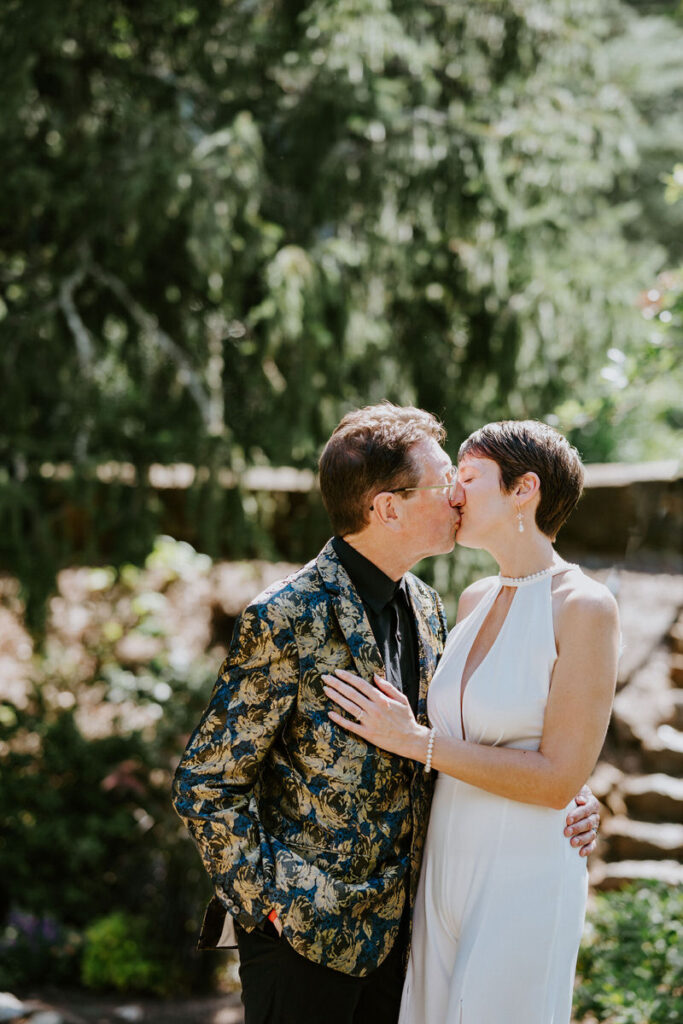 A wedding couple kissing in front of a rock staircase. 