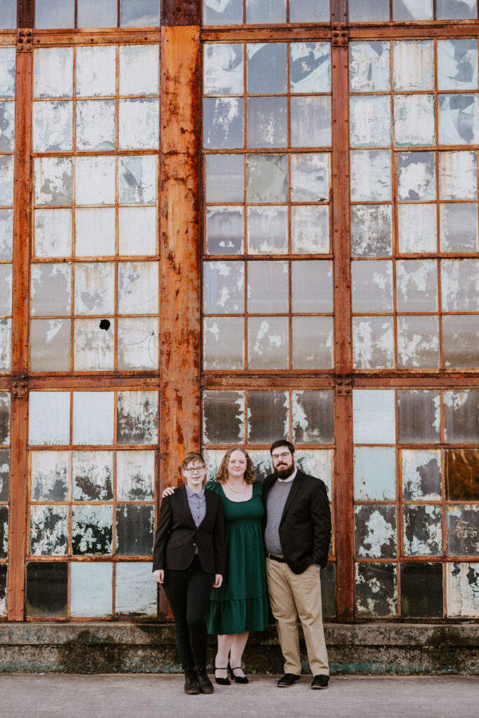 Two parents standing with their child in front of an industrial style building. 