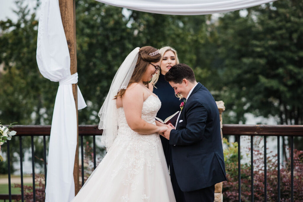 A couple holding hands while they say their vows during their wedding. 