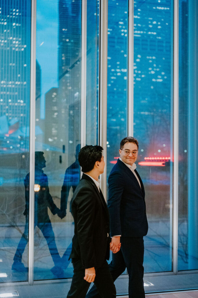 Walking side by side, the pair appear in mid-conversation in front of a floor-to-ceiling window with the city lights of Chicago as their backdrop.
