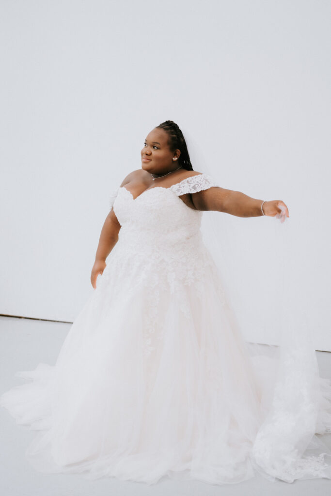 The bride strikes a playful pose, her wedding dress flowing around her, capturing the light-hearted and celebratory spirit of her special day.