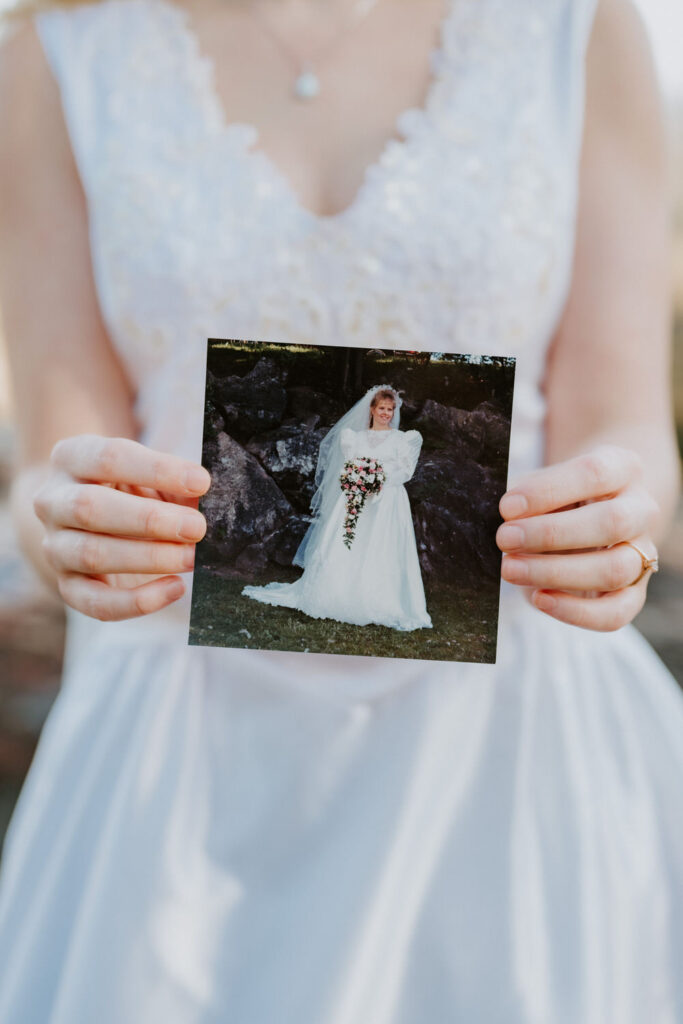 A bride holds an image of another in a wedding gown.