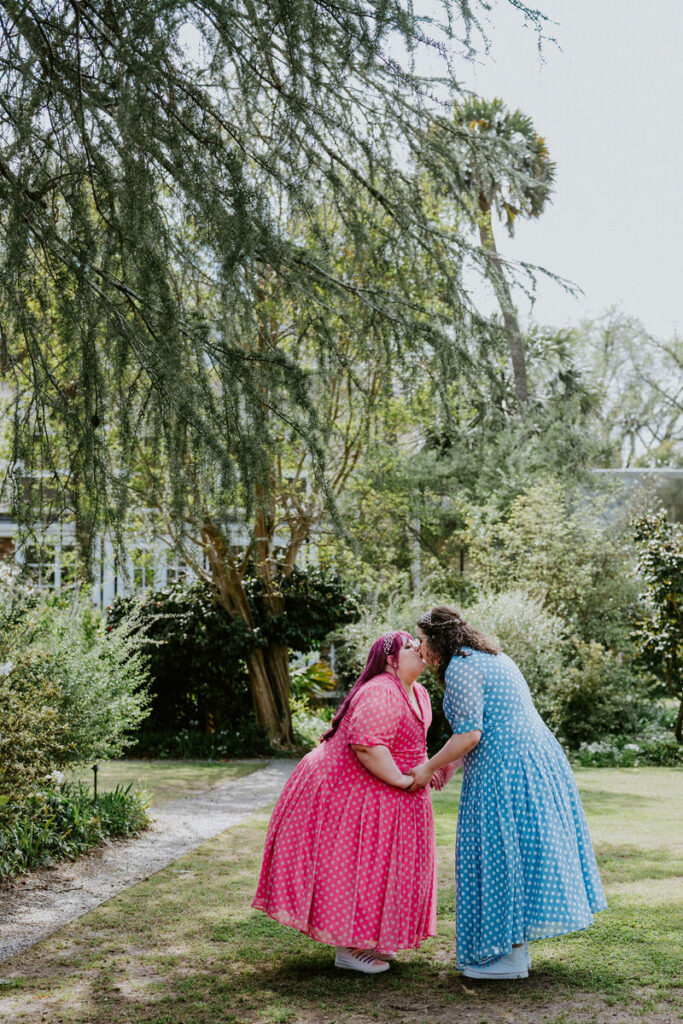 A couple holding hands and kissing in a garden. 