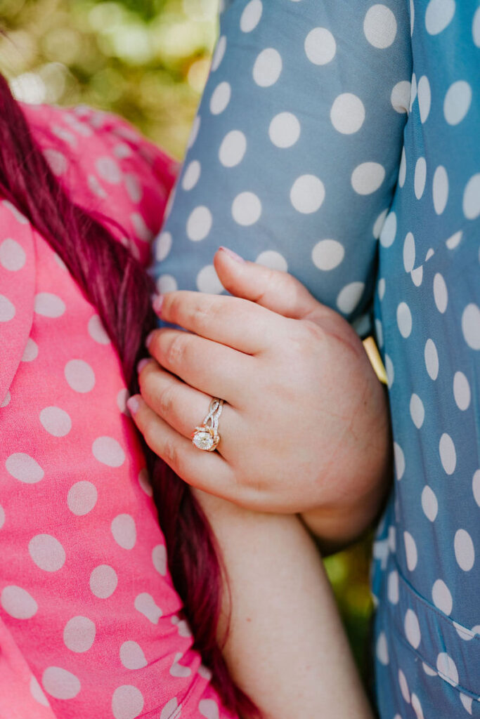 A close up of a hand wrapped around another person's arm showing off an engagement ring. 
