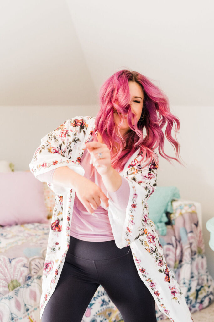 A person with pink hair dancing in a bedroom 
