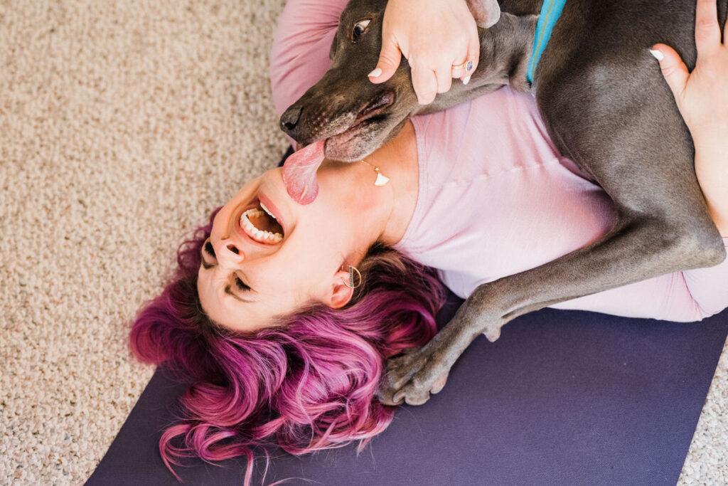 A person laying on the ground as a dog licks their face 