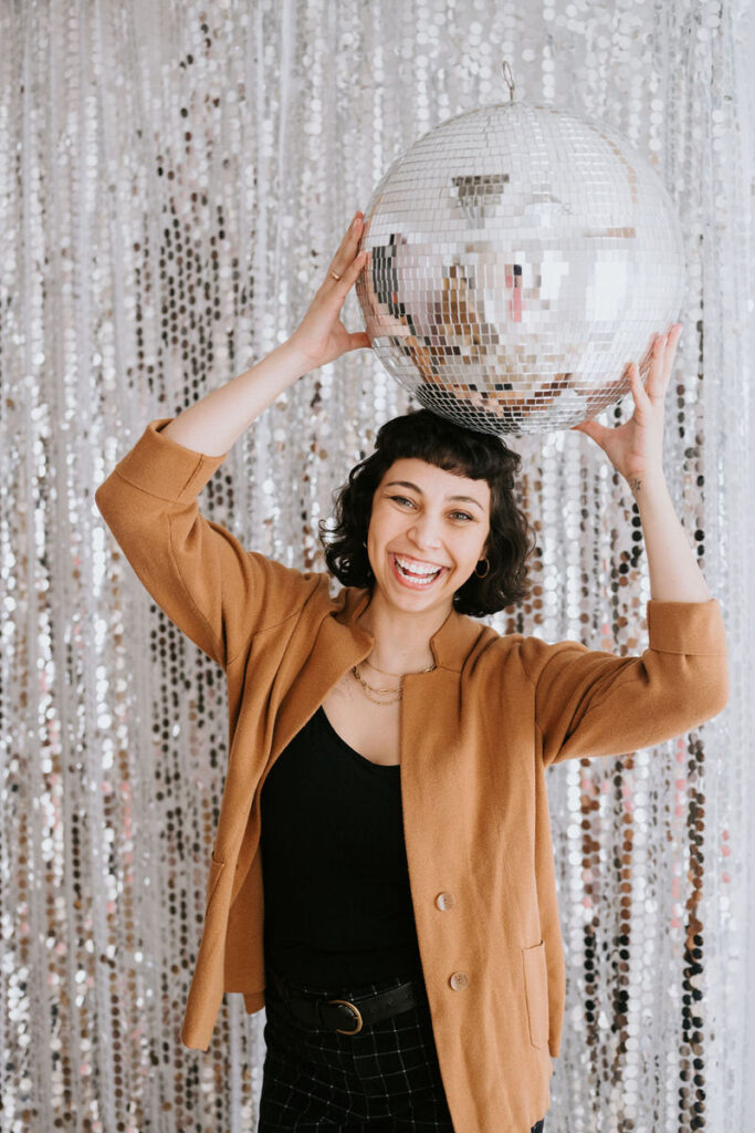 a person holding a disco ball on top of their head and smiling 