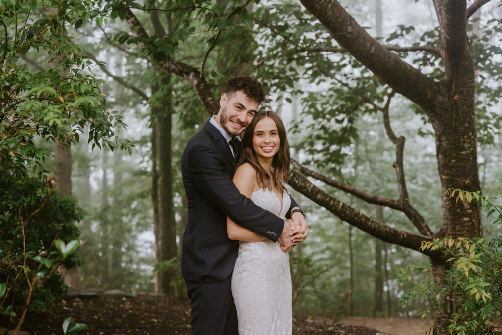 A couple poses with their arms wrapped around one another.