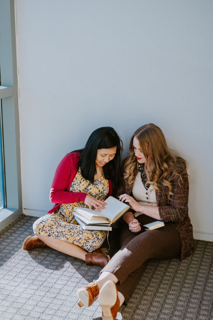 A couple sitting on the ground together looking at a book 