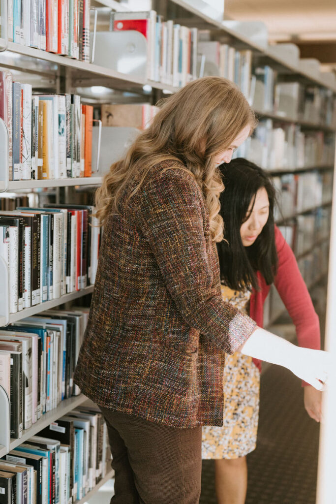 A couple in a library looking through the shelves 