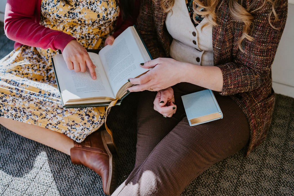 A close up of two people sitting together looking at a book