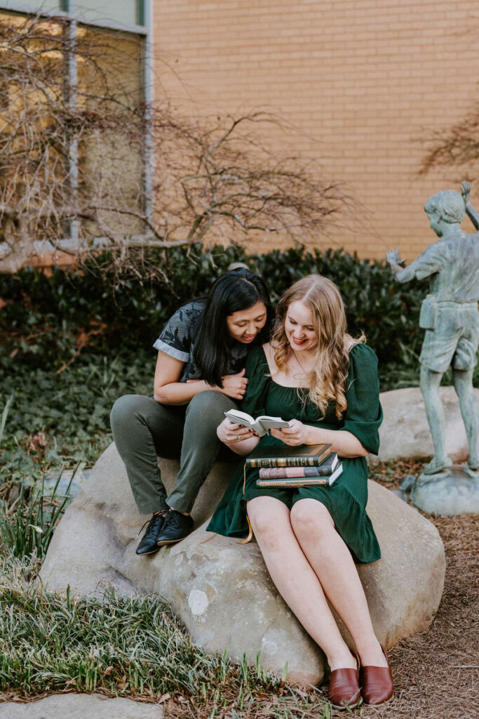 A couple sitting on a rock together looking at a book 