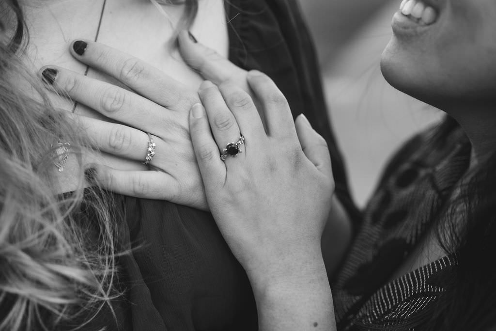 A close up of two hands with engagement rings on them 