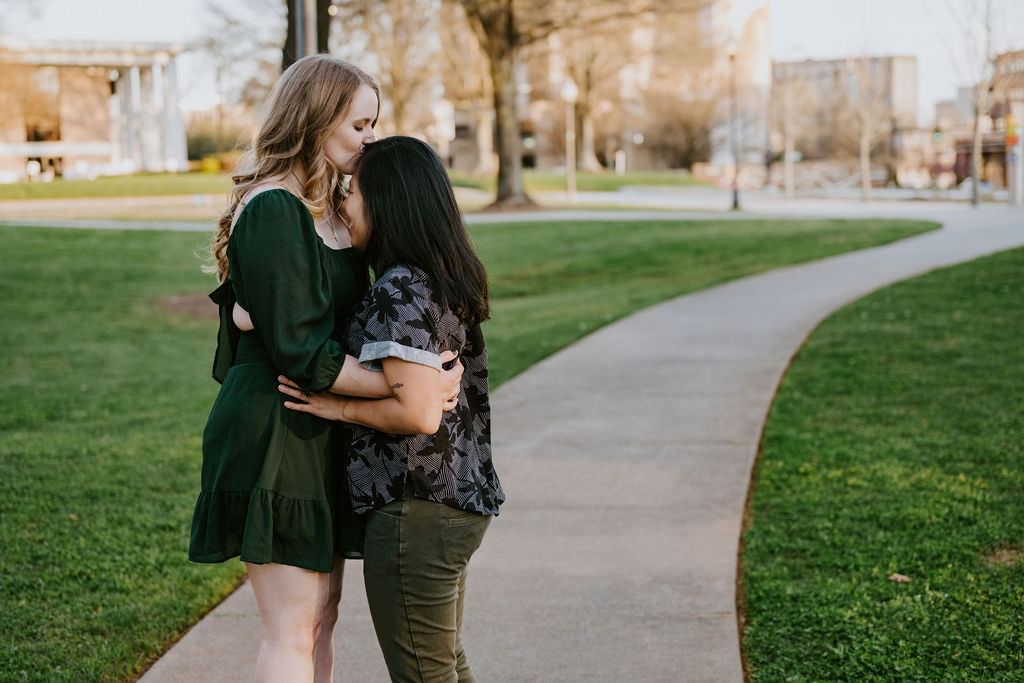 A person kissing their partner's head as they hug 