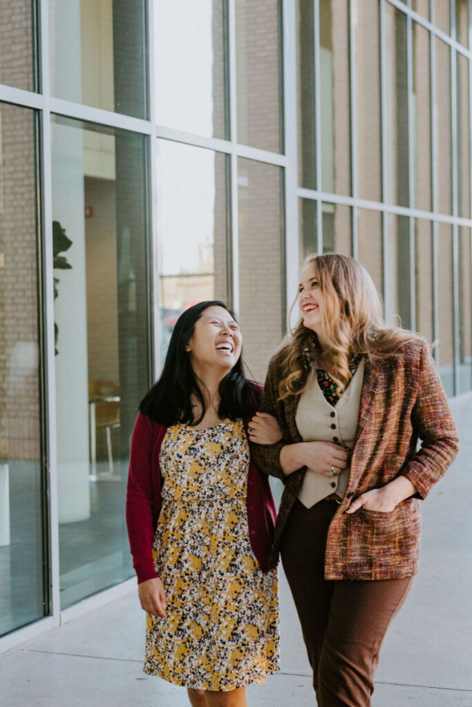 A couple with their arms looped together walking and laughing 