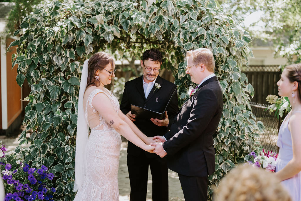 A wedding couple holding hands and saying their vows 