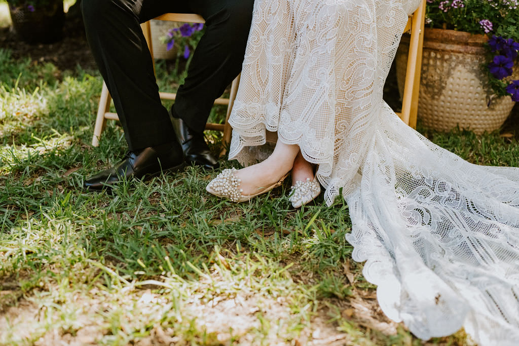 A close up of the feet of a wedding couple in a grassy area 
