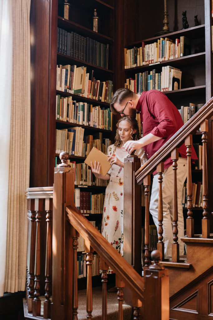 A couple standing near bookcases looking at a book together 