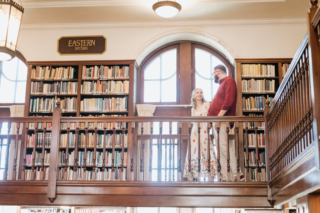 A couple walking across the top level of a library balcony. 