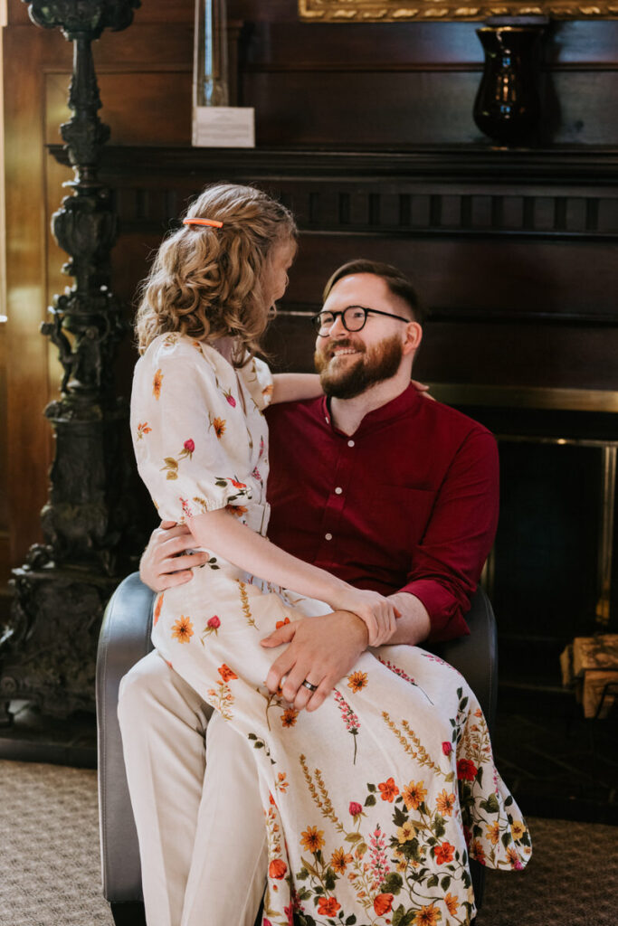 A person sitting on their partner's lap as they smile at each other. 
