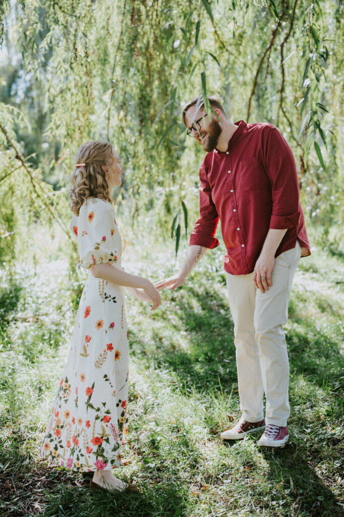 A couple standing in a field laughing together 