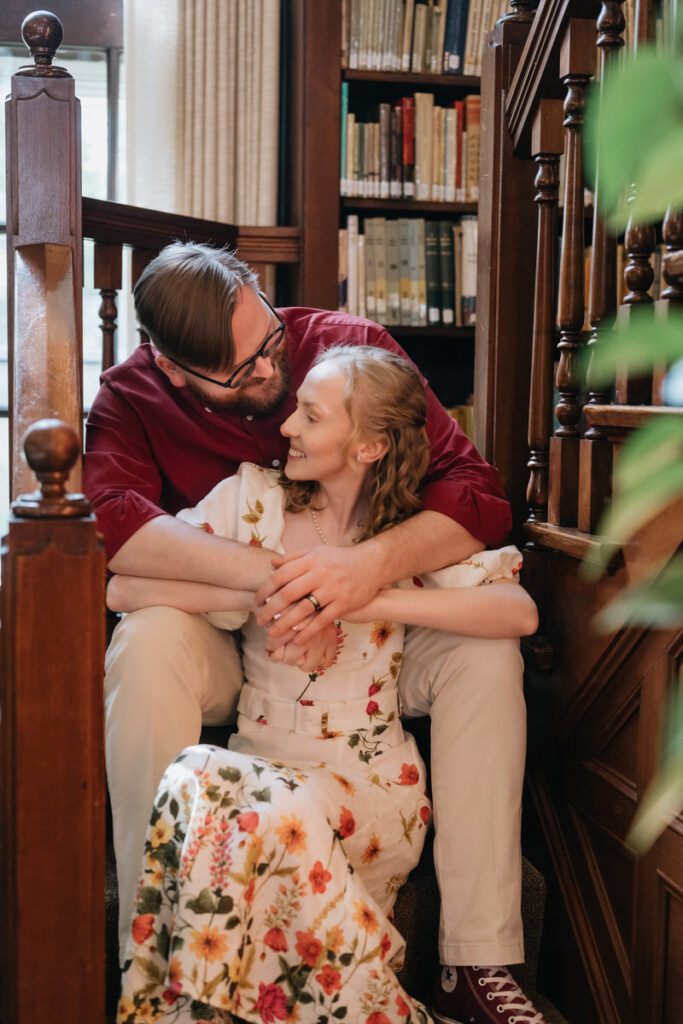 A couple sitting on a staircase together with their arms around each other. 