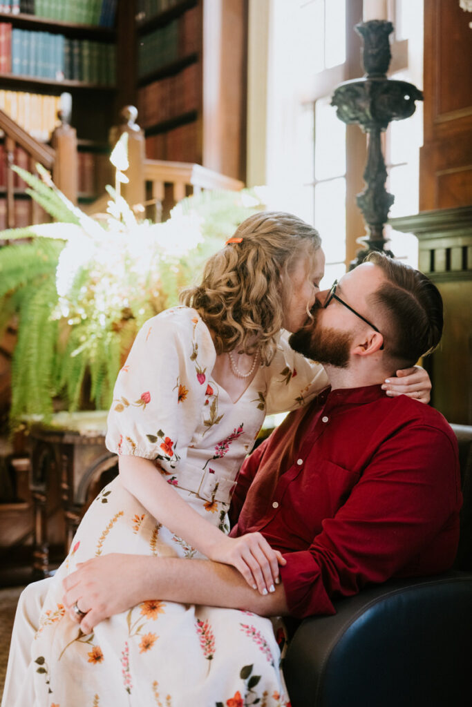 A person sitting on their partner's lap as they kiss. 