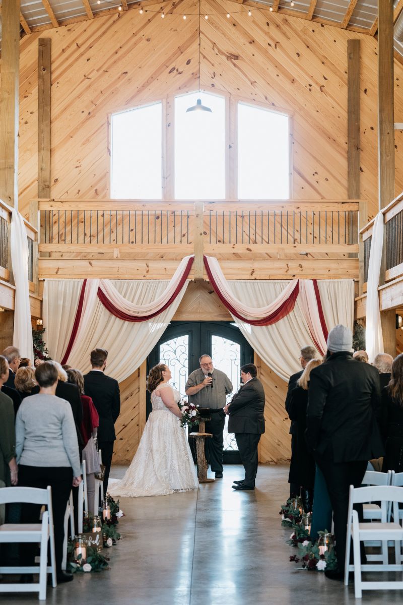 A couple at their wedding ceremony with their officiant and their wedding guests are standing up and watching them 