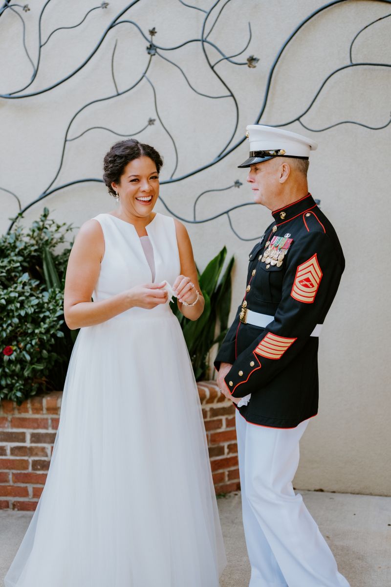 A woman in a white wedding dress doing a first look with her father 