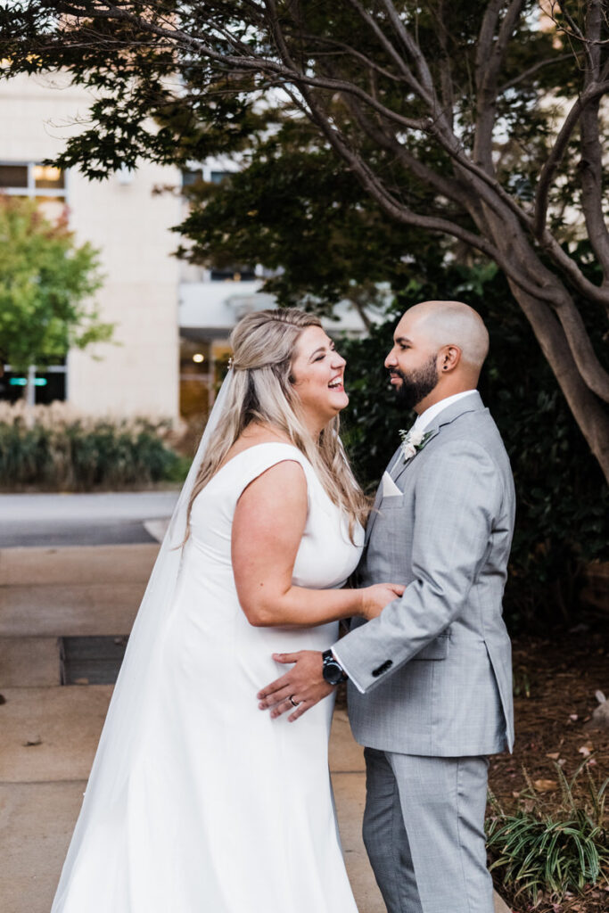 A newlywed couple laughing with their arms on each other 
