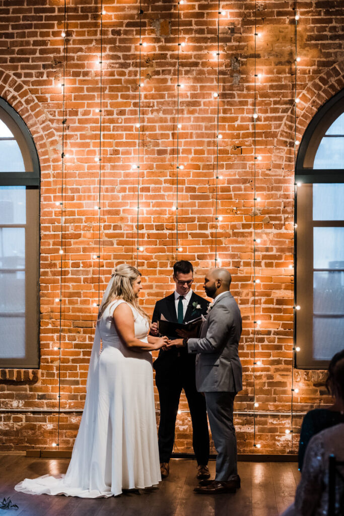 A couple holding hands as they say their vows 
