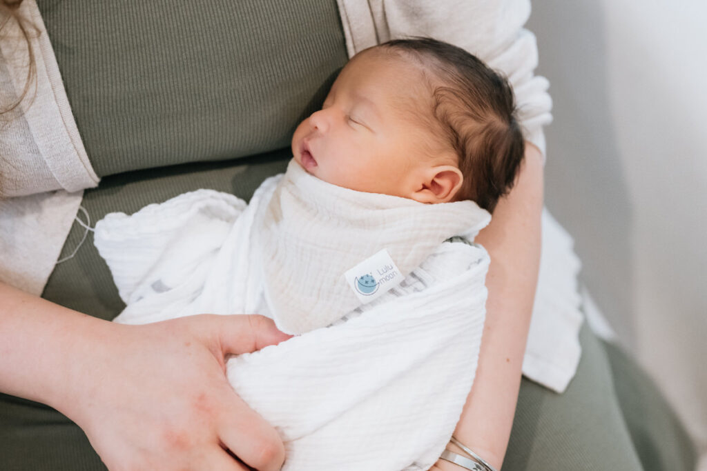 A newborn sleeping in their parent's arms