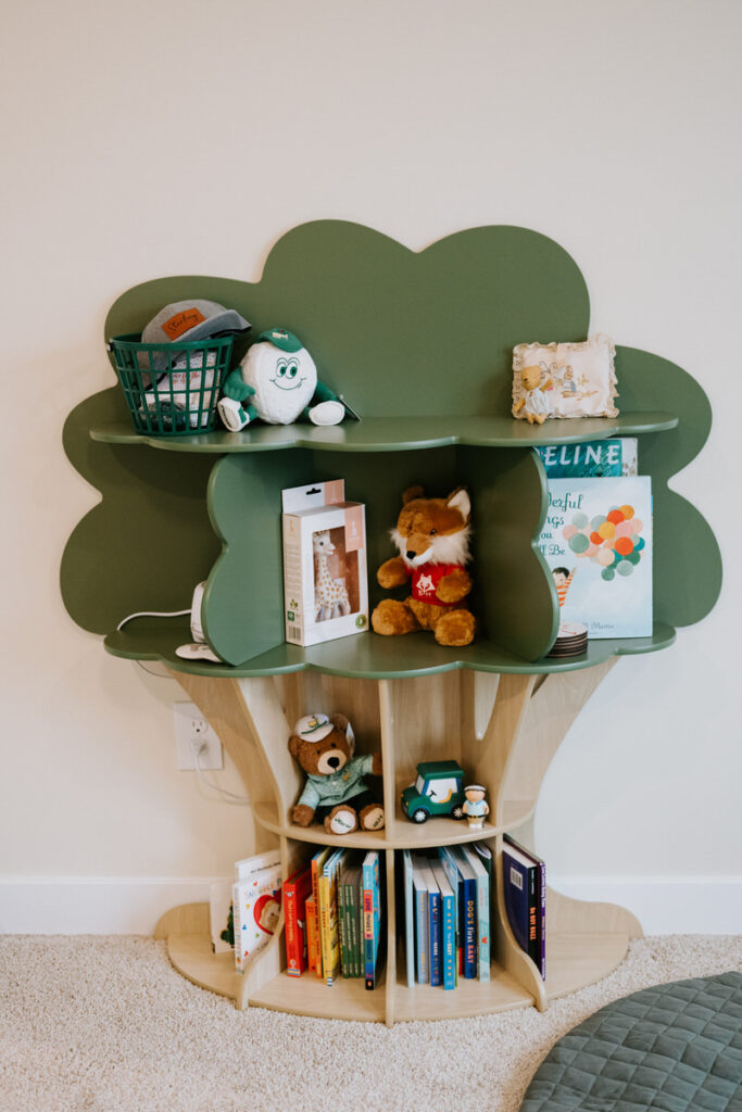 A tree-shaped bookcase covered in toys, stuffed animals, and books 