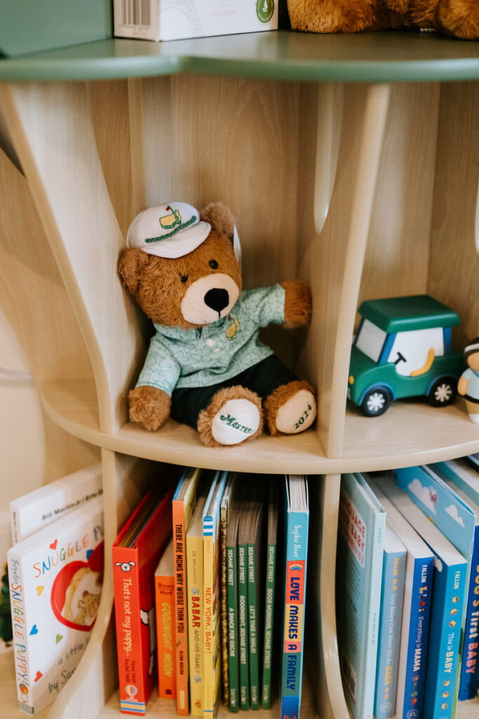 A small tree-shaped bookcase with children's books and toys on it 
