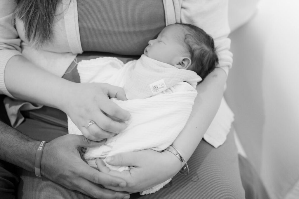 Black and white photo of a parents holding a newborn 
